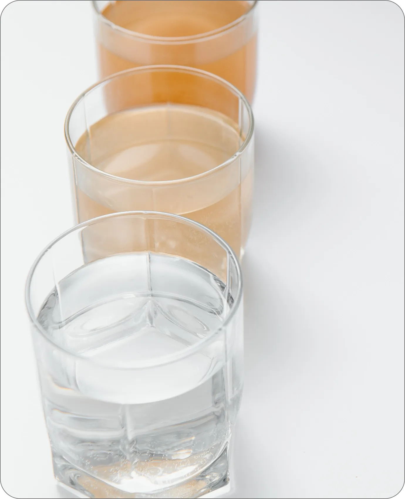 Three glasses comparing discolored untreated water to clear filtered water