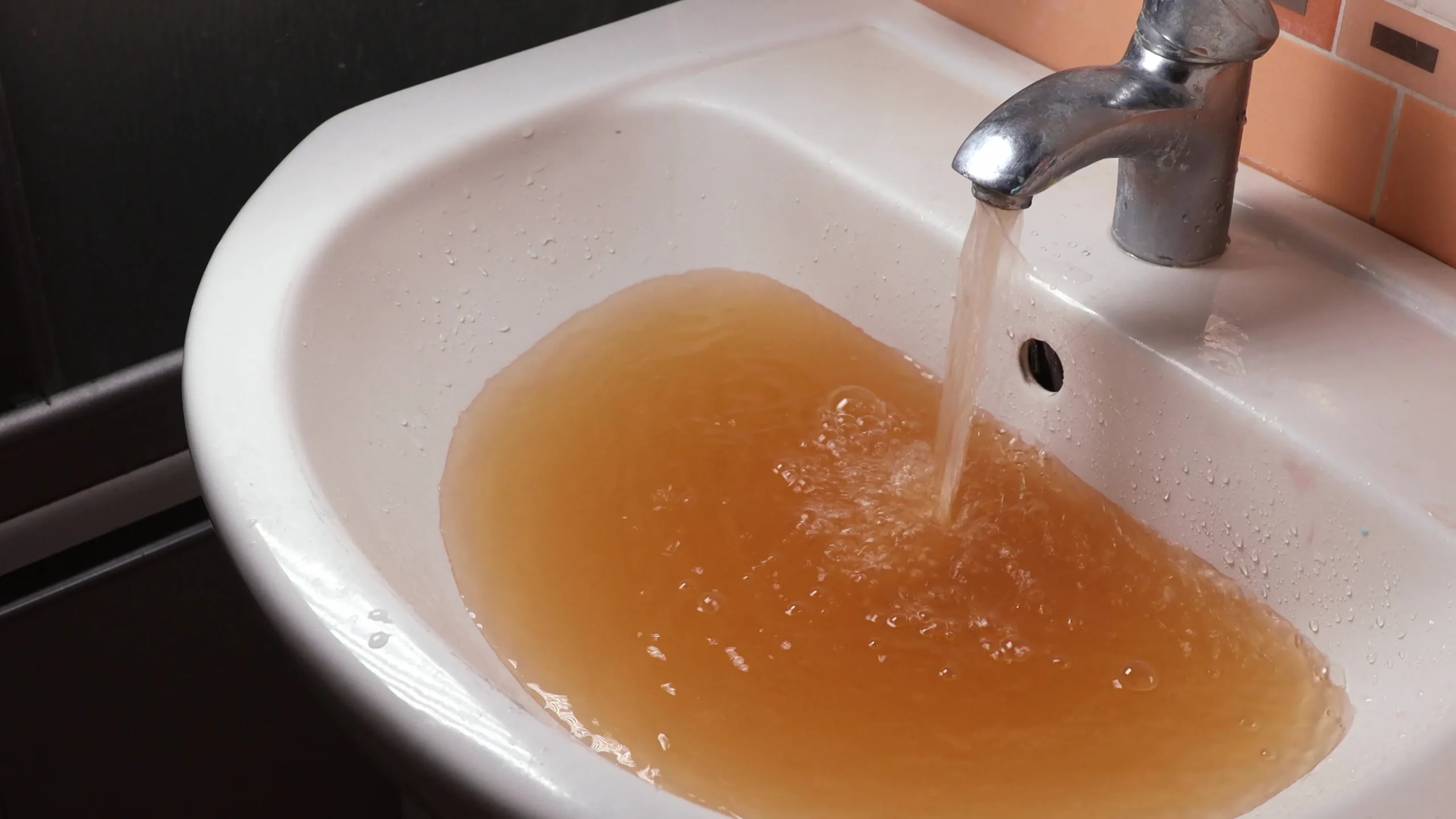Rusty, discolored water pouring from a tap due to iron in the water