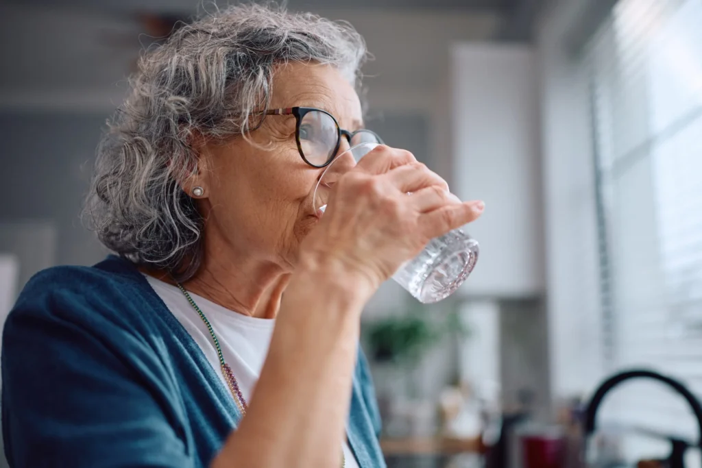 Homeowner pouring a glass of treated well water in a Southwestern Pennsylvania kitchen after ultraviolet disinfection