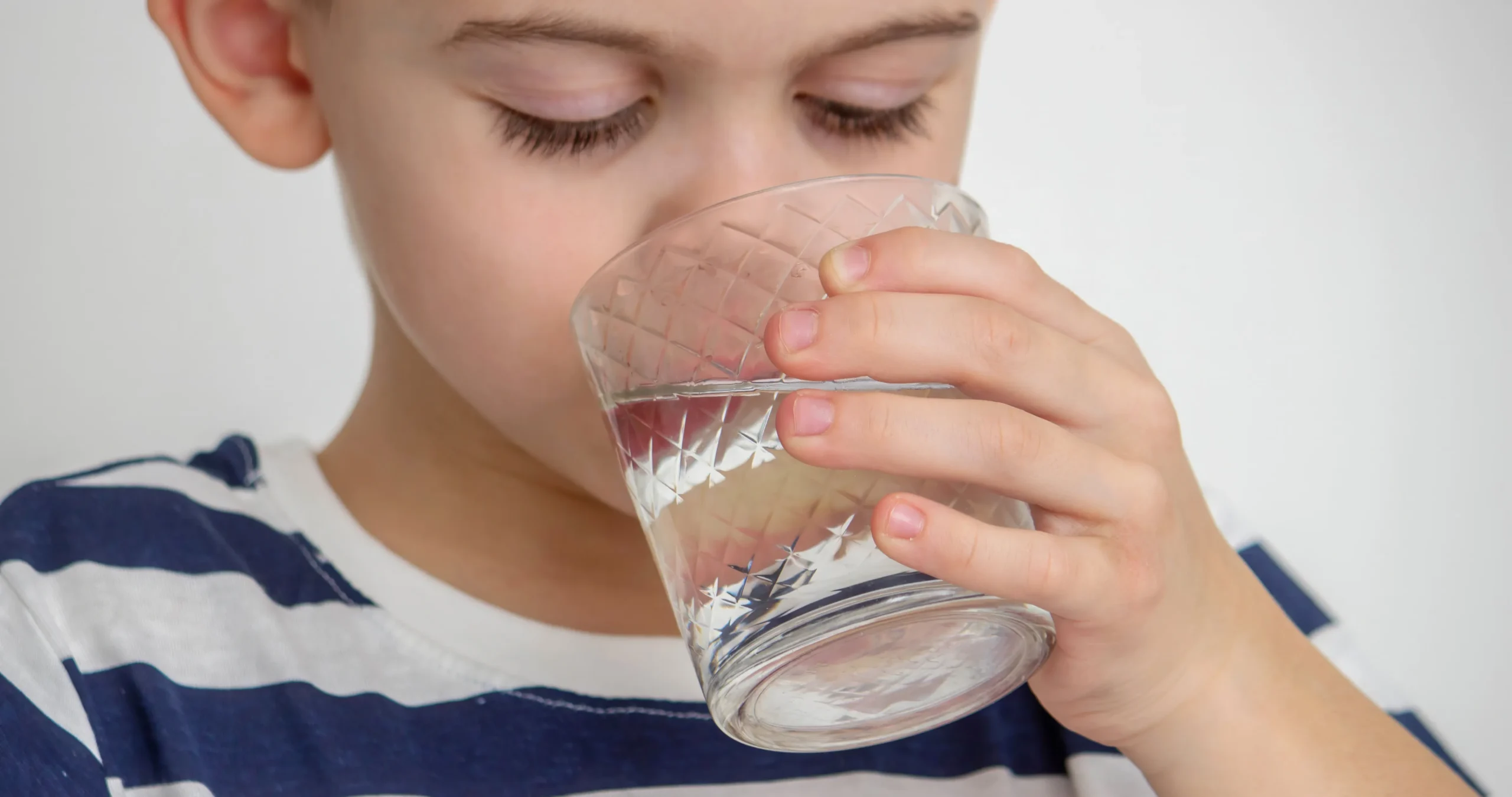 Young child drinking a glass of water at home