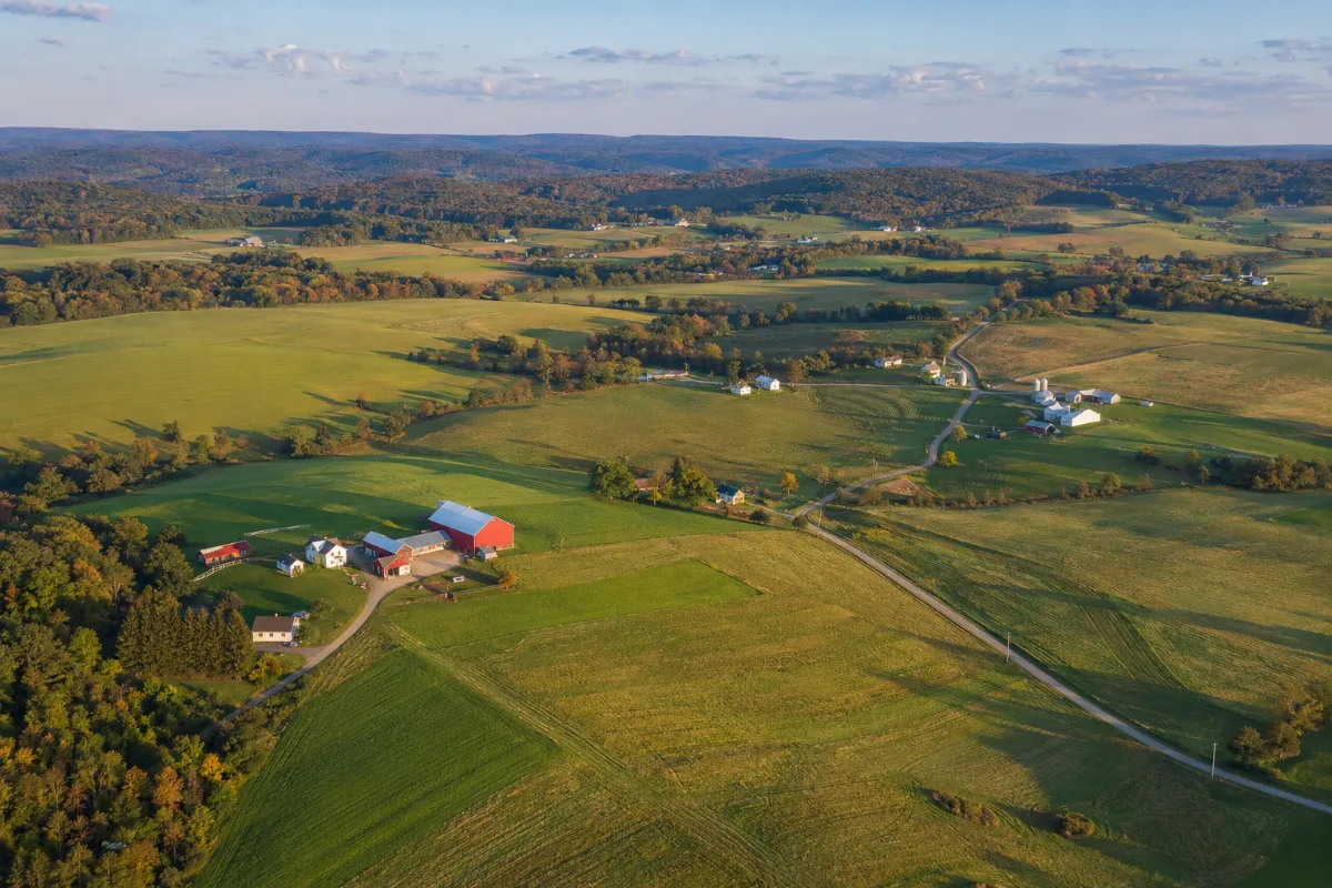 Aerial view of rolling farmland, red barns and wooded ridges in rural northern Indiana County, Pennsylvania near Marion Center and Clymer