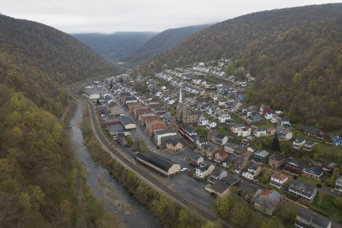 Aerial view of a former coal town in a narrow wooded mountain valley in northern Somerset County, Pennsylvania, with a creek and rail line along the valley floor