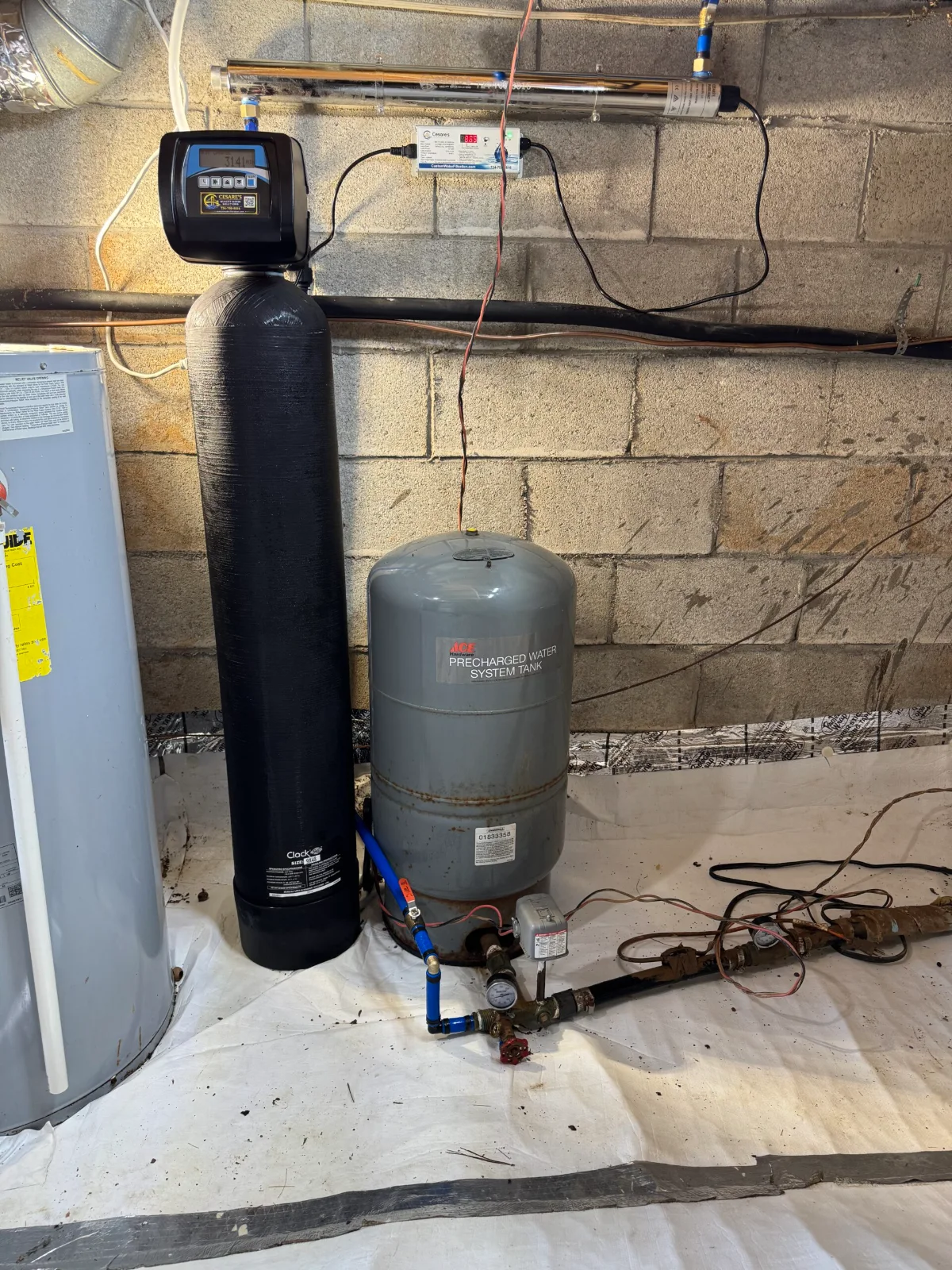 Cesare’s ultraviolet disinfection chamber and controller mounted above a whole-house treatment tank and well pressure tank in a Southwestern Pennsylvania basement.